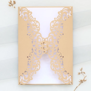 Macro detail of laser cut wedding invitation with golden twine on blue fabric background