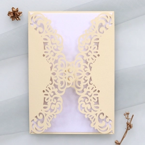 Detail of laser-cut cream invitation sleeve with elegant floral patterns and mesh background