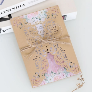Close-up of laser-cut kraft paper wedding invitation with floral card and jute twine