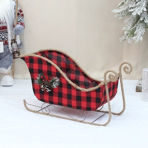 Close-up of red and black buffalo plaid Christmas sleigh with pine cones and cedar needles