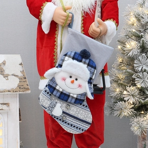 Close-up of gray knit Christmas stocking with snowman, plaid hat and metal bells