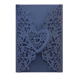 Macro shot of dark blue laser cut invitation card with intricate floral heart pattern