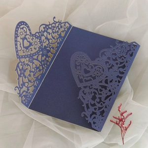Detail of navy blue laser-cut wedding invitation featuring heart and floral motifs