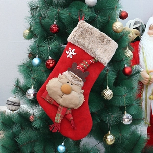 Detail of 3D reindeer plush on red velvet Christmas stocking hanging on a tree