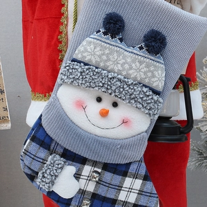 Close-up of blue knit Christmas stocking with 3D snowman and festive metal bells