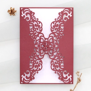 Detailed laser-cut European floral patterns on a dark red invitation over white cardstock