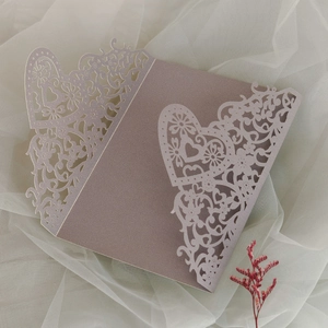 Detail of laser-cut lavender wedding invitation with heart patterns on soft white tulle