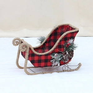 Christmas sleigh decor with red black plaid fabric, pine needles and snowy cones