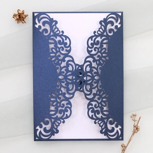 Close-up of laser-cut floral patterns on dark blue wedding invitation with white insert