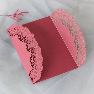 Dettaglio dell'intaglio laser floreale su invito di nozze in rosso scuro e rosa