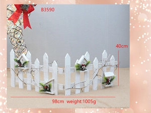Detail of white wooden Christmas tree fence featuring birdhouse and red bow decorations