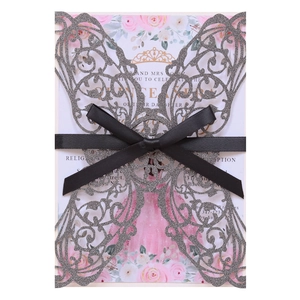 Macro detail of laser-cut silver glitter butterfly invitation with black satin bow