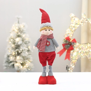 Detail of Christmas plush doll with red hat and striped scarf on festive background