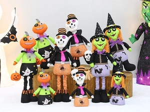 Close-up of plush Halloween dolls with pumpkin, skull, and witch embroidery on wood
