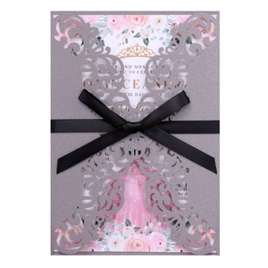 Detail view of laser-cut silver glitter invitation with a black satin bow and floral insert