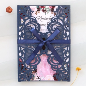 Détail d'invitation découpée au laser bleu marine avec ruban satiné et insert à motif floral