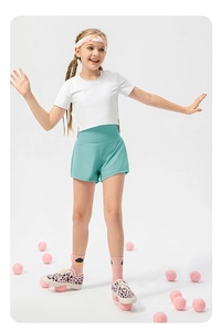 Girl's athletic set with white tee and mint green layered running shorts on studio background