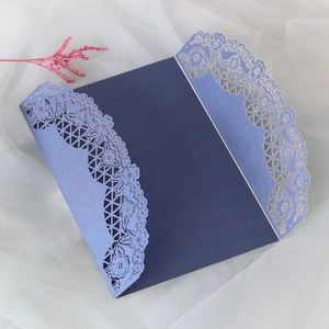 Dettaglio dell'invito di nozze blu scuro con eleganti motivi floreali traforati