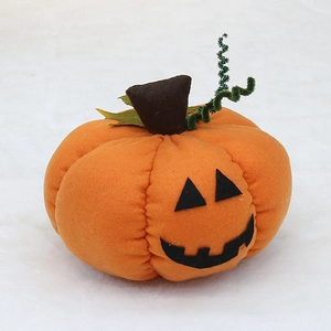 Close-up of orange plush Halloween pumpkin decoration with black felt face and green vine
