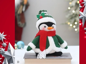 Détail de la peluche pingouin avec pull vert tricoté et écharpe rouge pour décor de Noël
