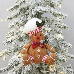 Gestrickter Lebkuchenmann-Weihnachtsanhänger mit Kochmütze an einem festlichen Baum