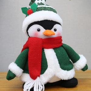Détail de la peluche pingouin de Noël avec pull en tricot vert et écharpe rouge