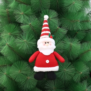 Close-up of a Santa plush ornament with red striped hat and knitted fabric on green tree