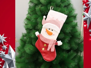 Detail of red velvet Christmas stocking with a 3D snowman hanging on a festive tree