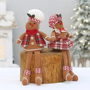 Detailed view of sitting gingerbread couple plush figures on wooden stumps for Christmas