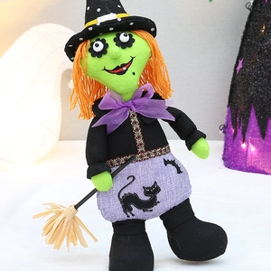 Plush Halloween witch doll with green face, orange hair, purple skirt and straw broom