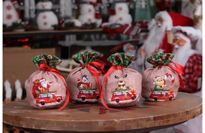 Detail of four burlap Christmas drawstring gift bags with classic holiday character motifs