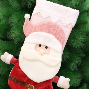 Detailed view of a pink knit Christmas stocking with a 3D plush Santa Claus on a green tree