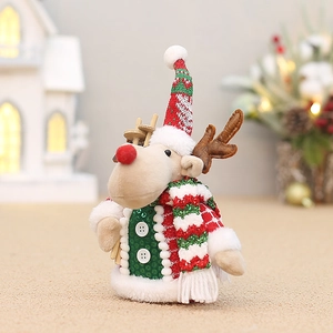 Détail d'un renne de Noël en peluche avec gilet à paillettes et mini traîneau en bois