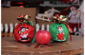 Two Christmas drawstring gift bags with snowman and reindeer patterns on a wooden table