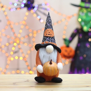 Macro view of Halloween gnome with spider web hat holding a pumpkin on wooden surface