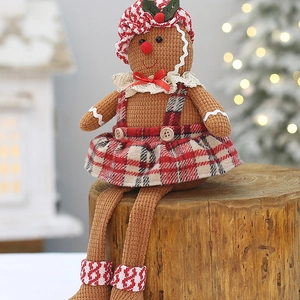 Christmas gingerbread man plush toy in red checkered dress sitting on a wooden stump