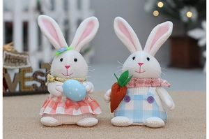 Detail of Easter bunny plush figures holding a blue spotted egg and bright orange carrot