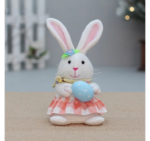 Detail of Easter plush bunny with yellow scarf and pink checkered dress holding a spotted egg