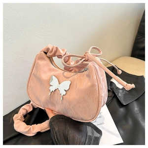 Detailed shot of pink pleated bag with silver butterfly charm on leather jacket