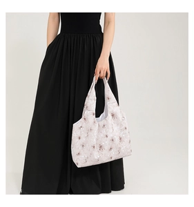 Détail d'un grand sac cabas avec imprimé floral porté par un mannequin en robe longue