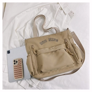 Vue à plat du sac cabas en nylon kaki avec broderie noire et grande poche frontale