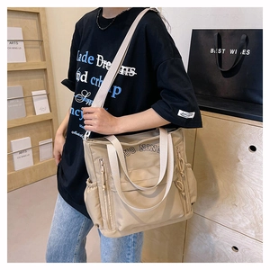 Détail d'un sac cabas en toile kaki avec fermetures éclair et lettrage imprimé