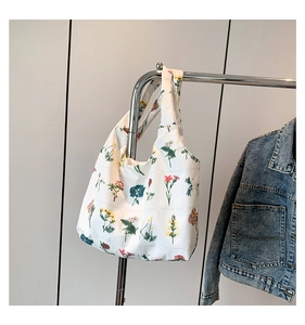 Vue détaillée d'un sac cabas en toile blanche avec imprimés floraux sur un support métallique