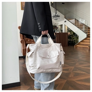 Détail du grand sac cabas en toile crème avec poche frontale et poches latérales pratiques