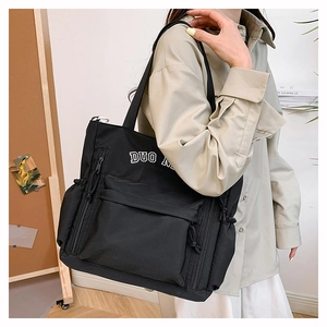 Détail du sac cabas utilitaire noir en toile avec poches multiples et broderie de lettres