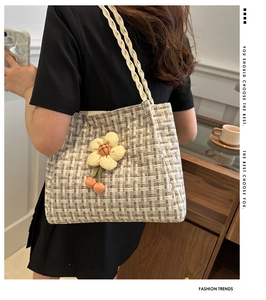 Vista dettagliata di una borsa tote in paglia intrecciata con fiori 3D su una modella