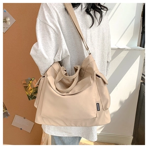 Détail du grand sac cabas en toile beige avec poche avant et bandoulière réglable