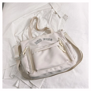 Détail du sac en toile avec broderie DUO NING et poches zippées sur le devant