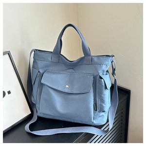 Detail of blue canvas tote bag showing side storage pockets and fashion fabric label