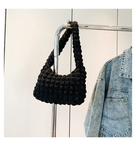 Vue détaillée du tissu à bulles noir d'un sac sous le bras suspendu sur un cintre